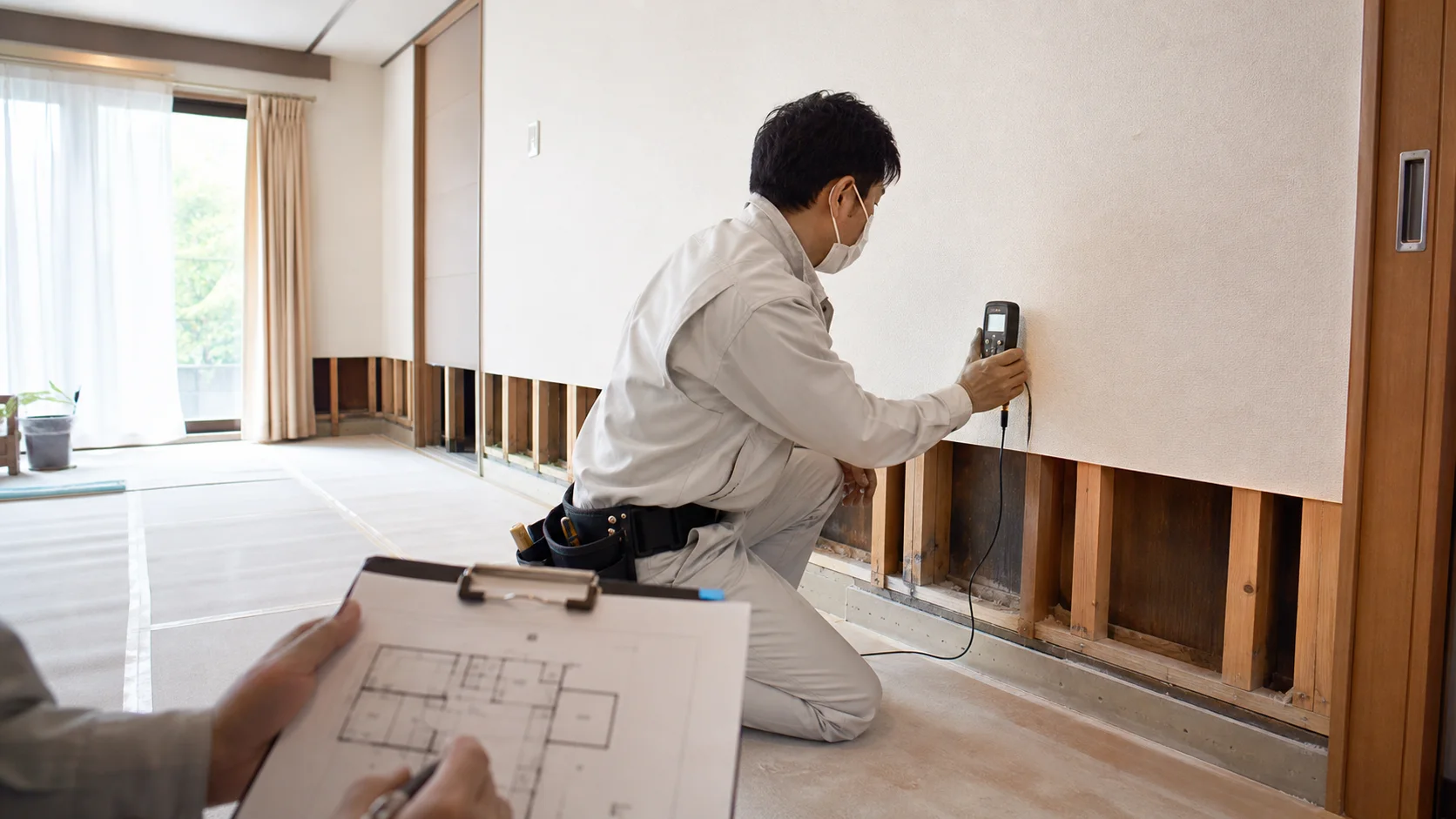 浸水後の住宅で内壁を開けて含水状態を測定する作業者の再現イメージ
